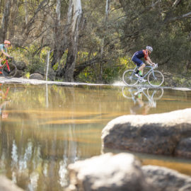Cyclists ride through a river in Beechworth