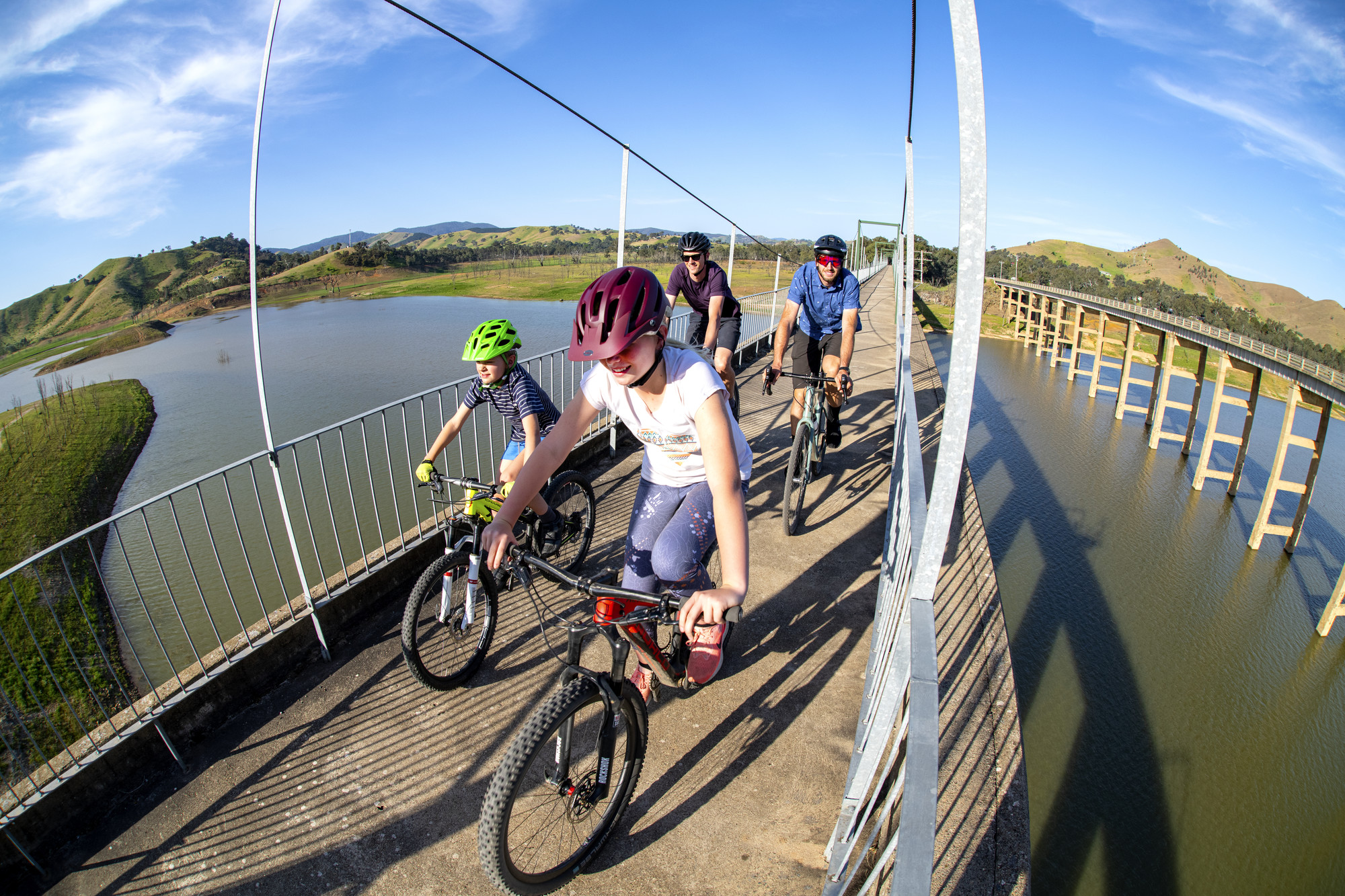 A family of cyclists riding across the Bonnie Doon Bridge on the Great Victorian Rail Trail